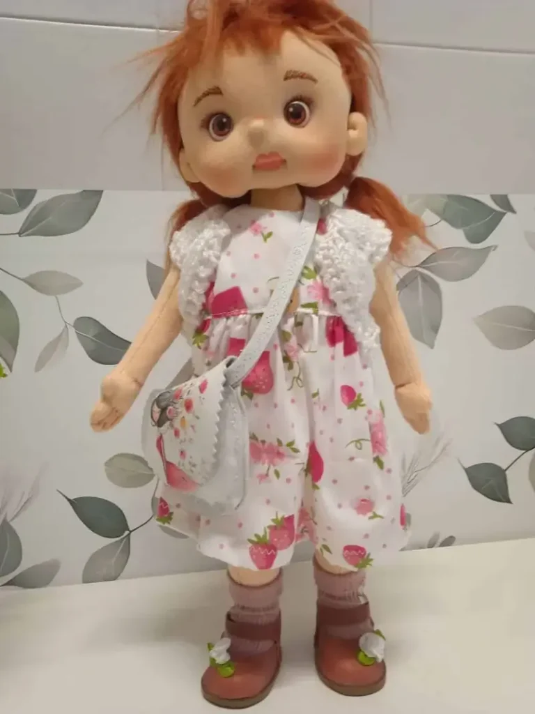 : Mu&ntilde;eca de tela articulada soft hecha a mano con vestido de fresas, rebeca blanca y zapatos merceditas de cuero color miel.