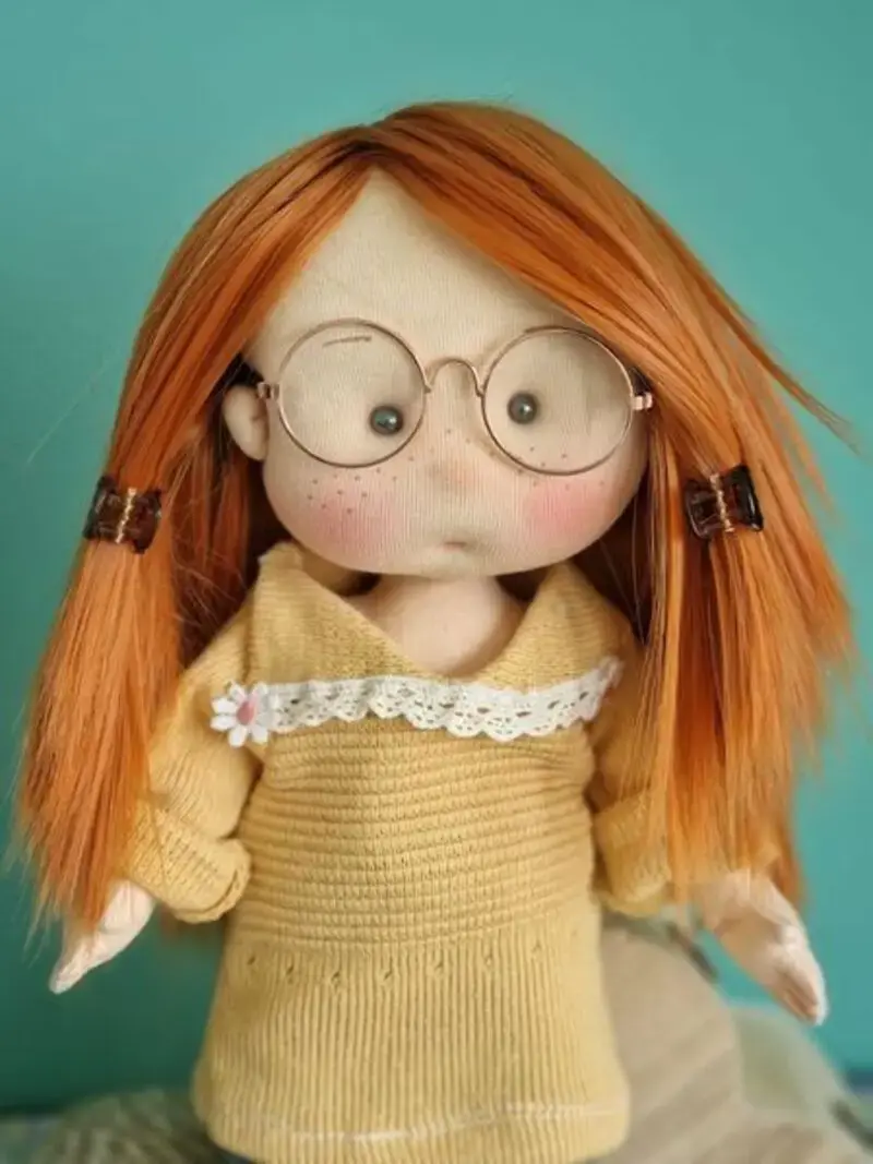 Mu&ntilde;eca de tela artesana Maryxeniss articulada, vestida con jersey de punto amarillo, minifalda y gafitas.
