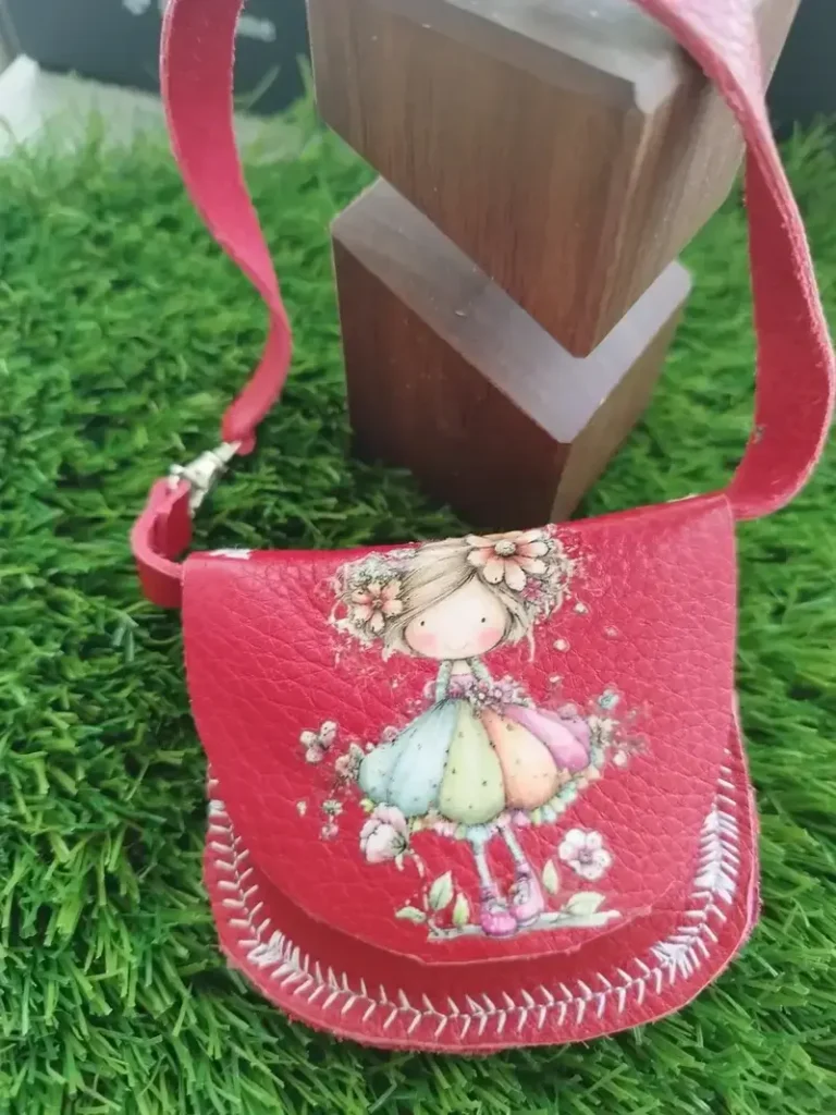 Bolso bandolera de piel aut&eacute;ntica en color rosa con correa ajustable para mu&ntilde;ecas de tela.