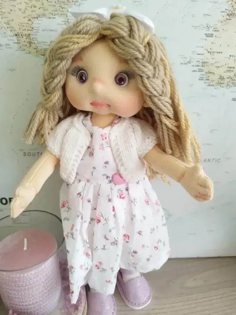 Plano general de mu&ntilde;eca de trapo tipo soft con rebeca blanca hecha a mano y vestido floral.