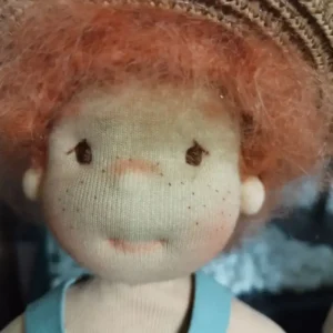 Primer plano de un mu&ntilde;eco de peluche con pelo naranja y un sombrero de paja trenzada.
