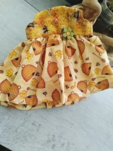 Primer plano del tejido de algod&oacute;n de uno de los vestidos para mu&ntilde;ecas de trapo artesanas mostrando el estampado de abejas.